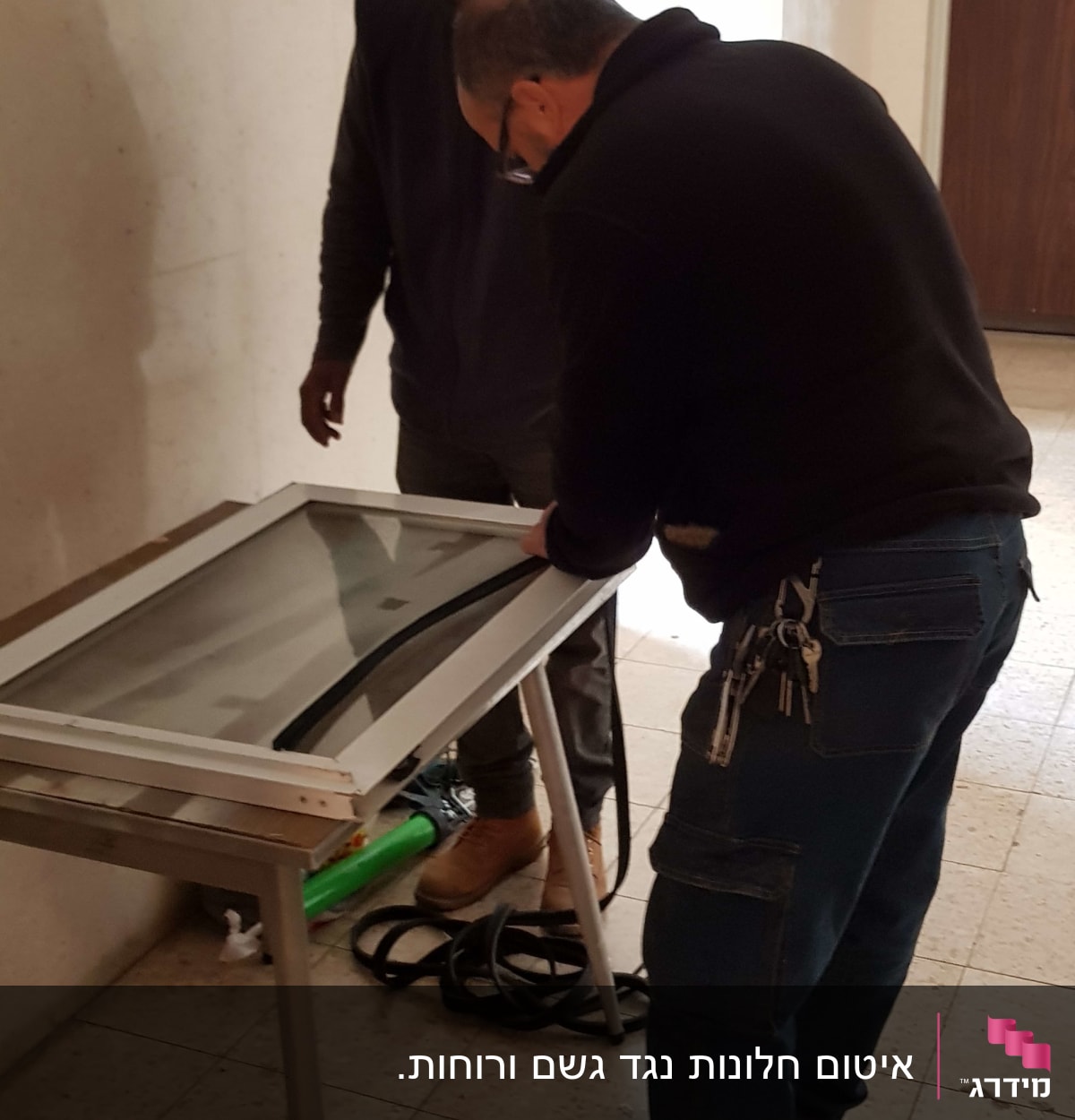 שני אנשים עובדים על מסגרת אלומיניום עם זכוכית